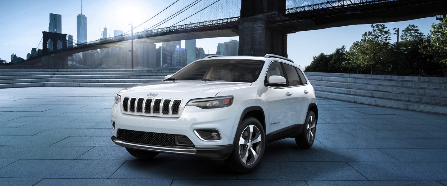 The 2020 Jeep Cherokee parked in a downtown area with a bridge overhead.